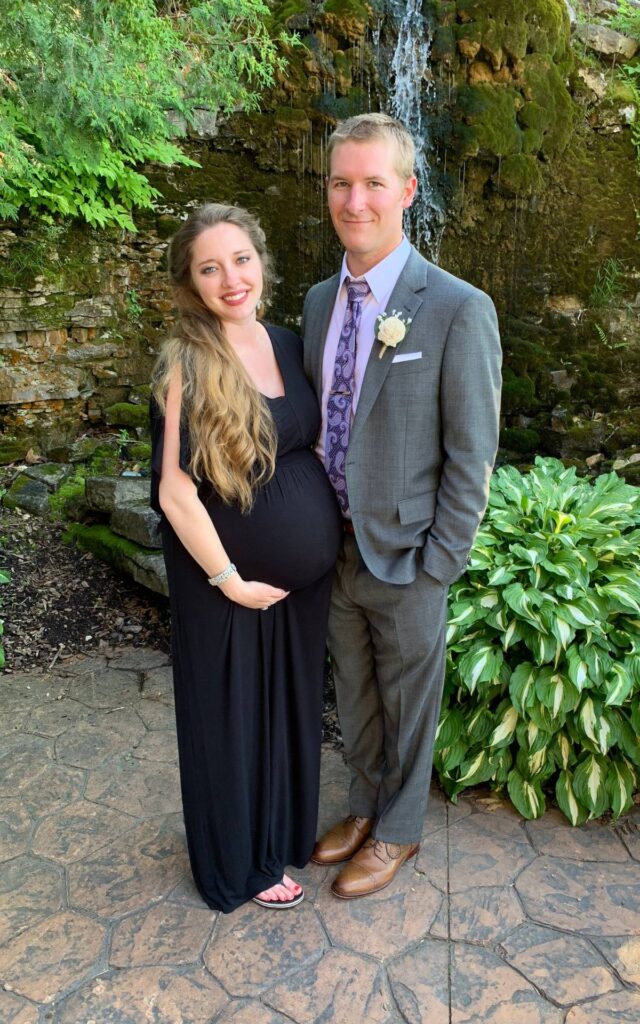 Pregnant woman and man standing in front of a decorative waterfall