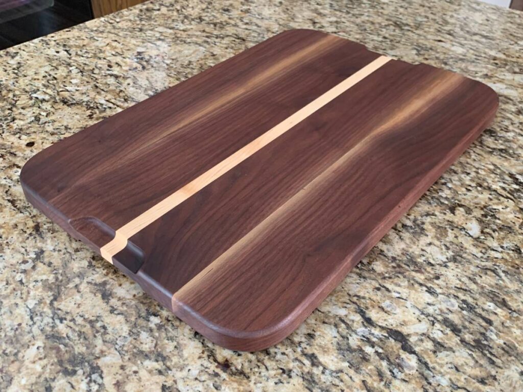walnut and maple cutting board laying on a granite countertop